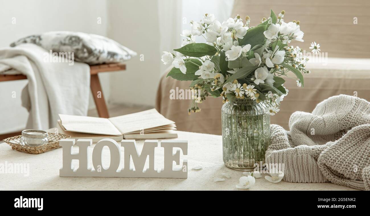 Stillleben mit einem Blumenstrauß, einem Buch und einem hölzernen dekorativen Wort Home. Stockfoto