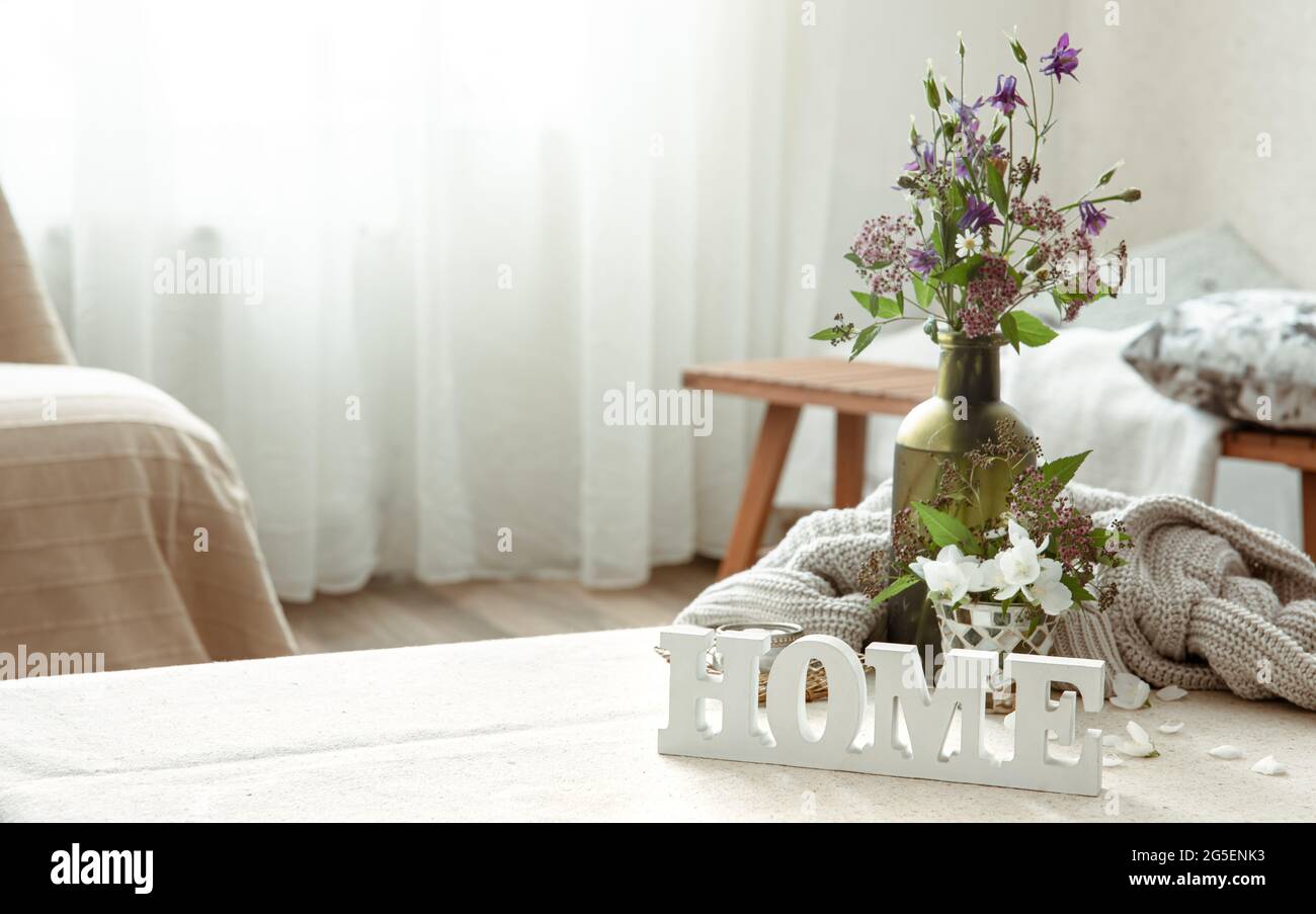 Stillleben mit einem Blumenstrauß, einem Buch und einem hölzernen dekorativen Wort Home. Stockfoto