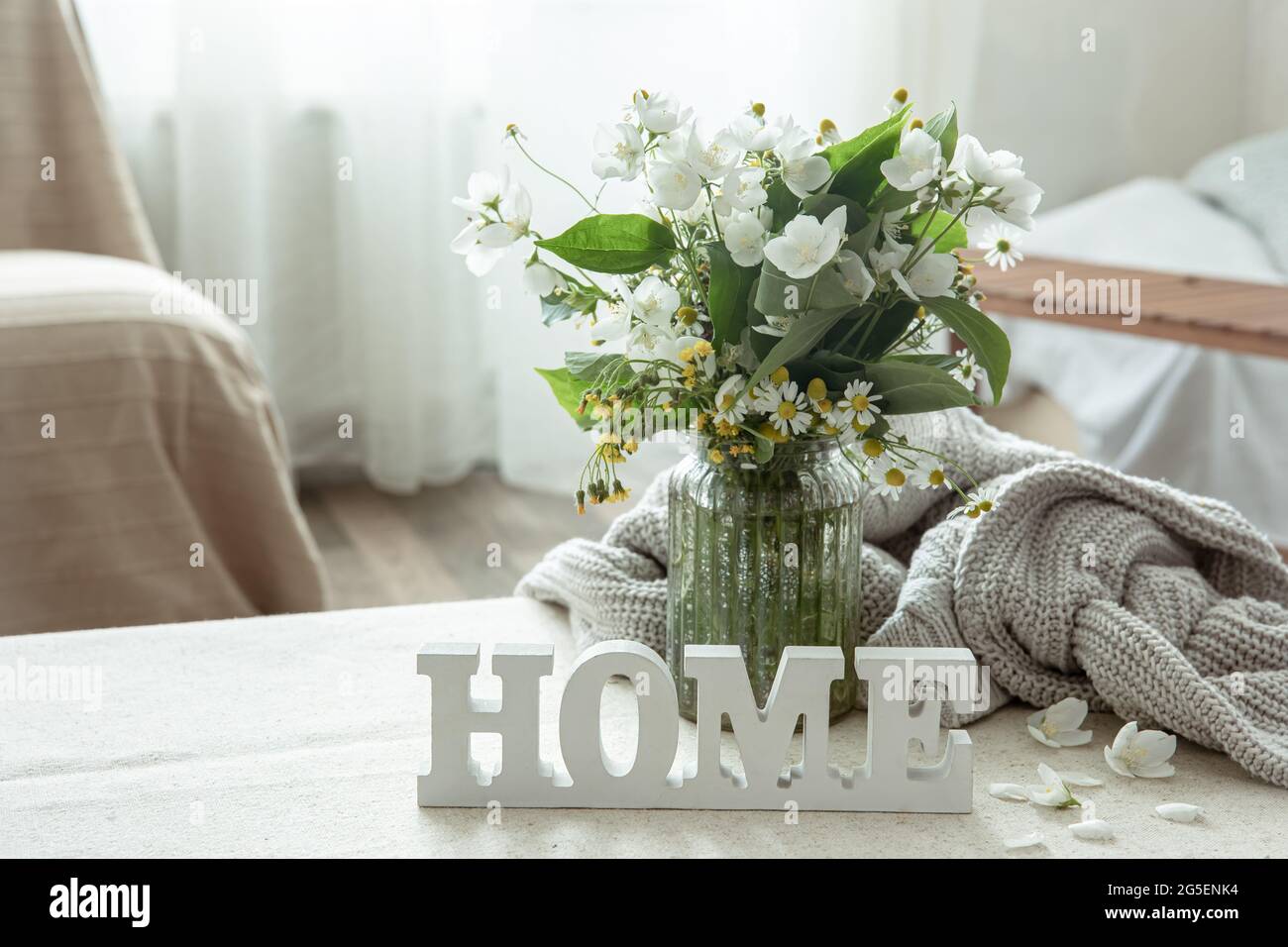 Stillleben mit einem Blumenstrauß, einem Buch und einem hölzernen dekorativen Wort Home. Stockfoto