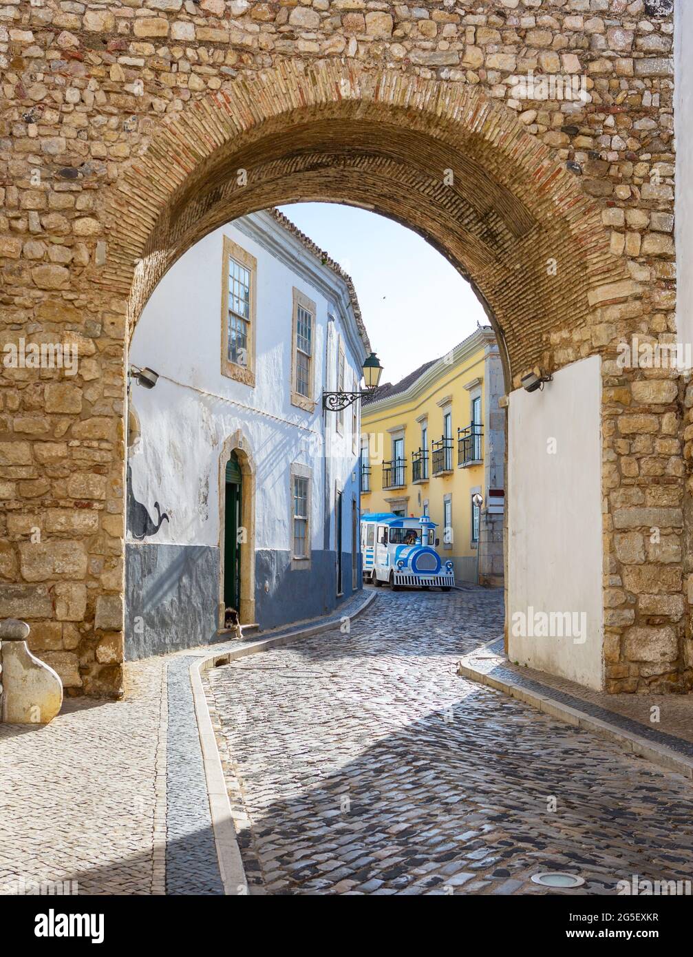 Schmale, gewundene Straße in der historischen Altstadt von Faro, Algarve, Portugal. Sightseeing-Bus im Hintergrund. Stockfoto