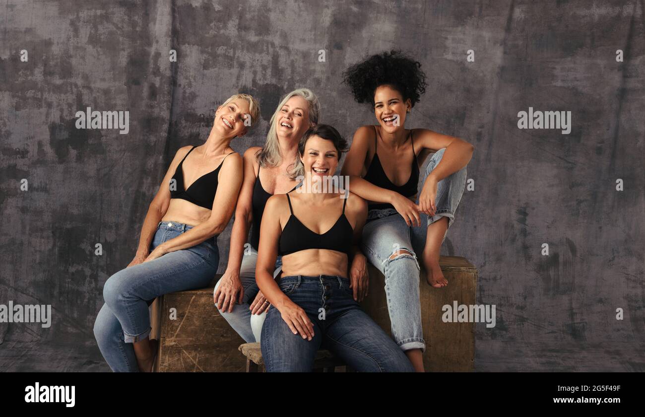 Eine kurze Aufnahme verschiedener Frauen, die zusammen lachen. Vier körperpositive Frauen unterschiedlichen Alters feiern ihren natürlichen Körper, während sie wieder Jeans tragen Stockfoto