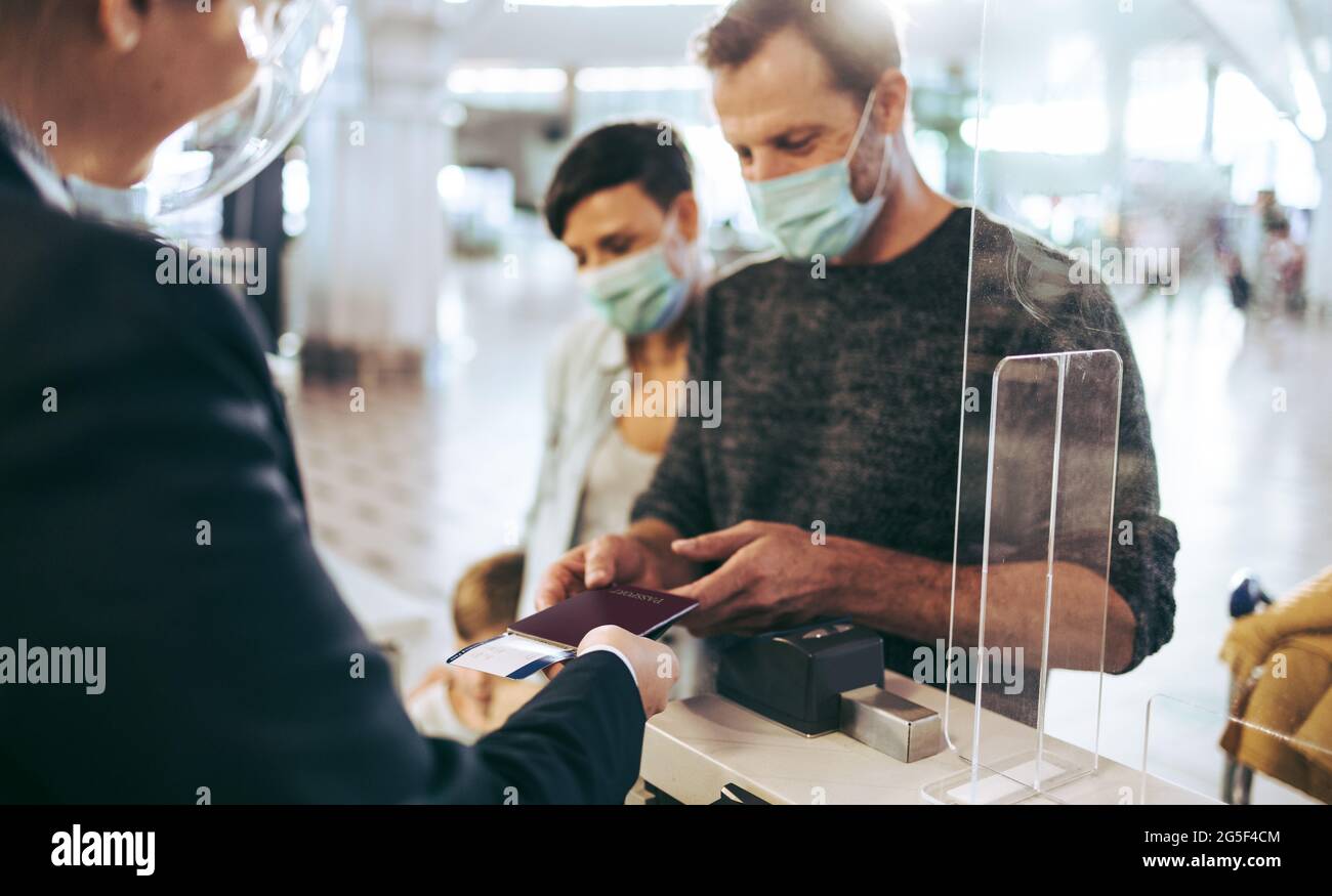 Reisender, der während der Pandemie am Check-in-Schalter am Flughafen seinen Reisepass aushändigt. Mann am Check-in-Schalter am Flughafen. Stockfoto