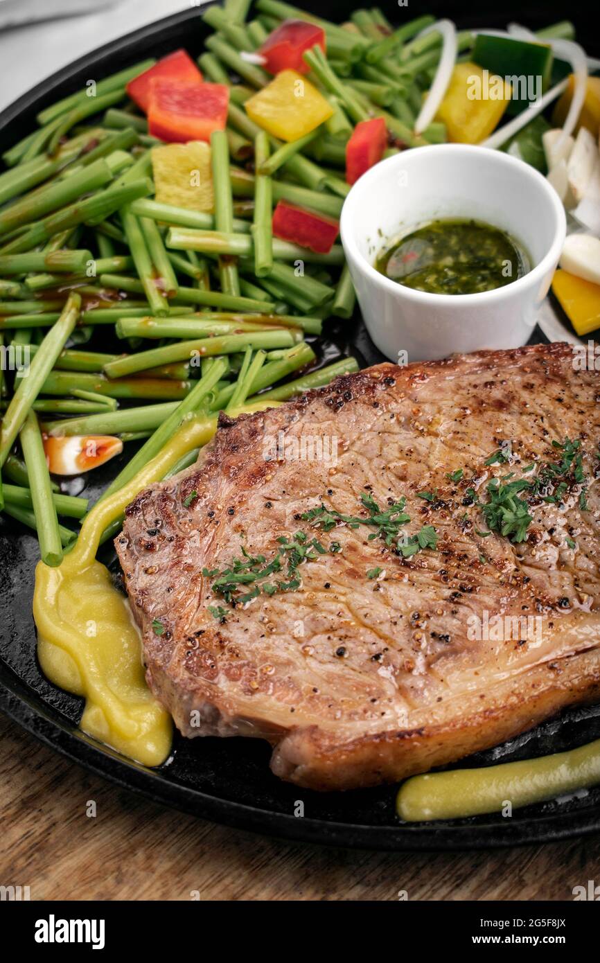 Bio-Rinderfilet-Steak-Sizzler auf heißer Platte Mit gemischtem Gemüse und Chimichurri-Sauce Stockfoto