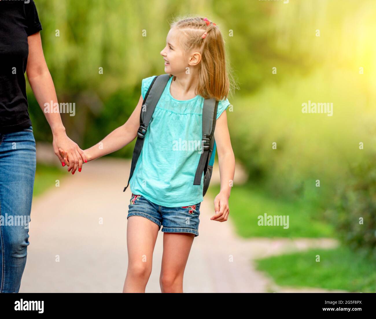 Kleine Schülerin, die mit Mutter im Park läuft Stockfoto