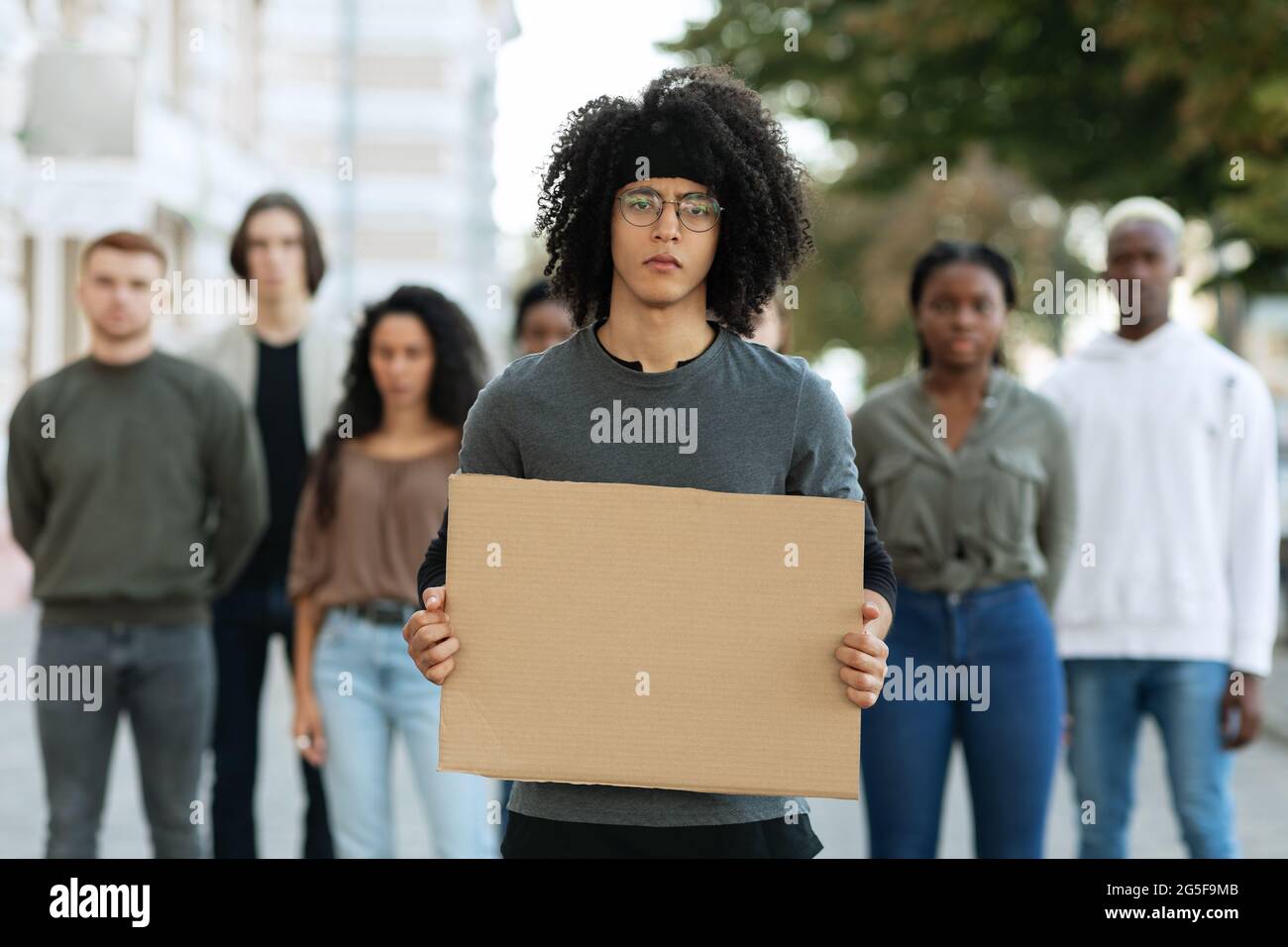 Aktiver afroamerikanischer Mann führt eine multirassische Gruppe von Demonstranten auf der Straße an. Internationale vielfältige Gruppe von Menschen mit leeren Plakaten protes Stockfoto