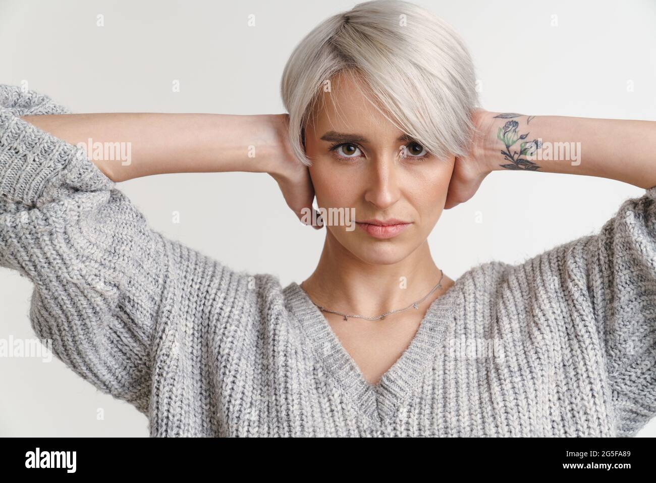 Weißhaarige junge Frau posiert mit Händen hinter ihrem Hals, isoliert über der weißen Wand Stockfoto