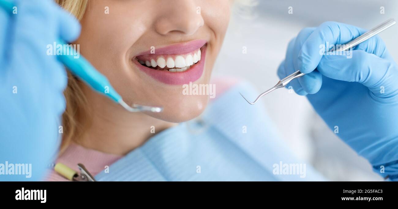 Nahaufnahme einer Patientin, die ihre schönen weißen Zähne zeigt, während sie in der Zahnklinik behandelt wird, Zahnarzthände in Gummihandschuhen, die auch Zahnärzte halten Stockfoto