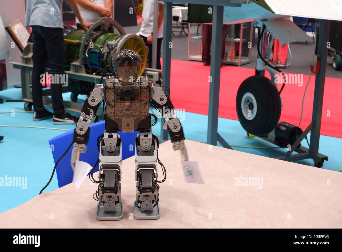 Kleiner, menschlich geformter Roboter, der Banner auf einer Industriemesse hält Stockfoto