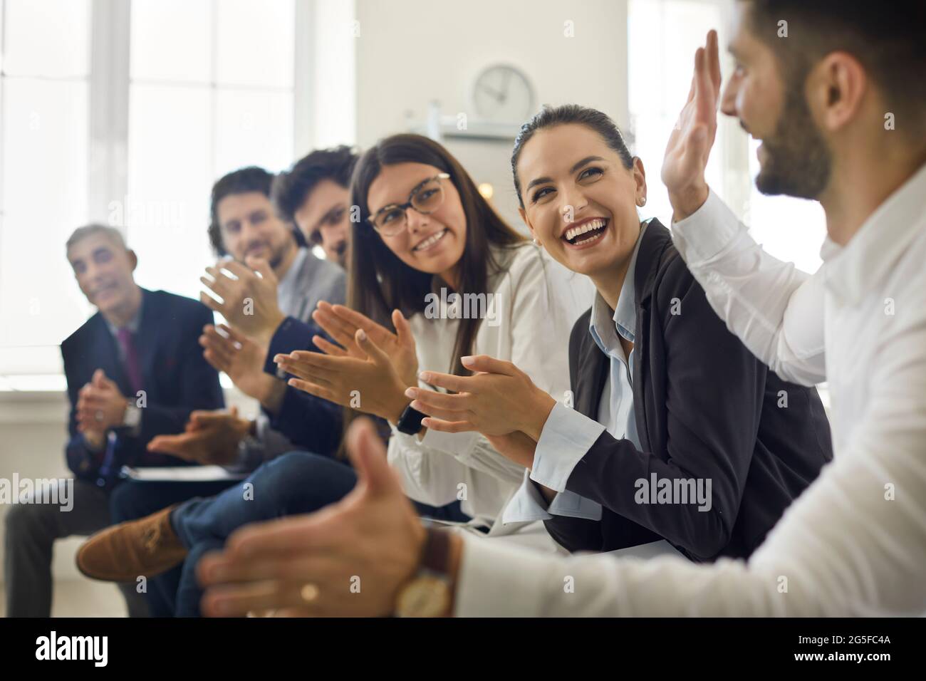 Glückliche Geschäftsleute applaudieren Kollegen bei Präsentationen oder Firmenbesprechung Stockfoto
