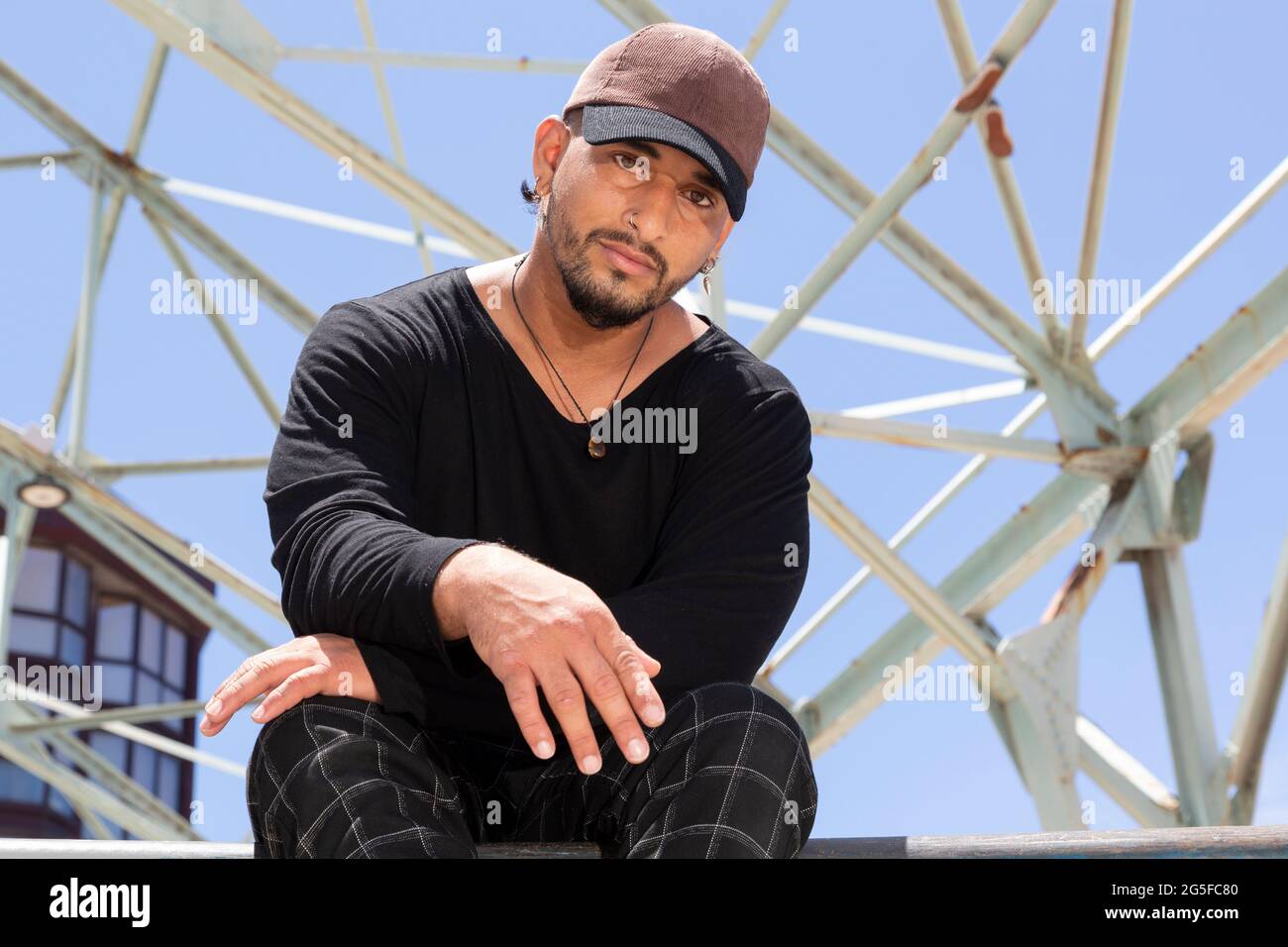 Porträt eines jungen lateinamerikanischen Akrobaten-Straßentänzers, der in einem Skatepark sitzt. Stockfoto