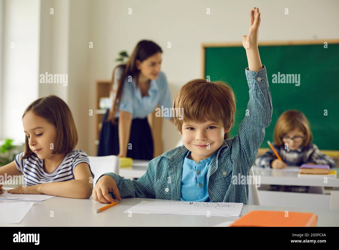 Porträt eines cleveren Grundschüler, der lächelnd die Hand zur Kamera hebt Stockfoto