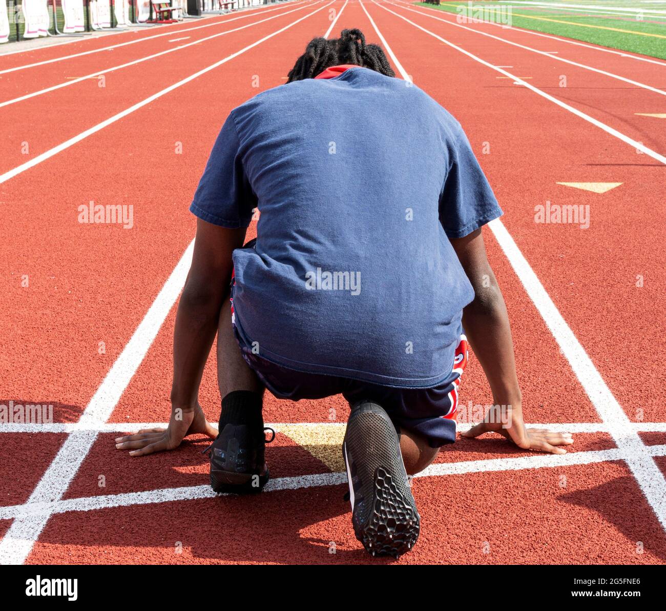Rückansicht eines Highschool-Laufes und Sprintläufers, der bereit ist, während des Trainings auf der Spur die Strecke zu laufen. Stockfoto