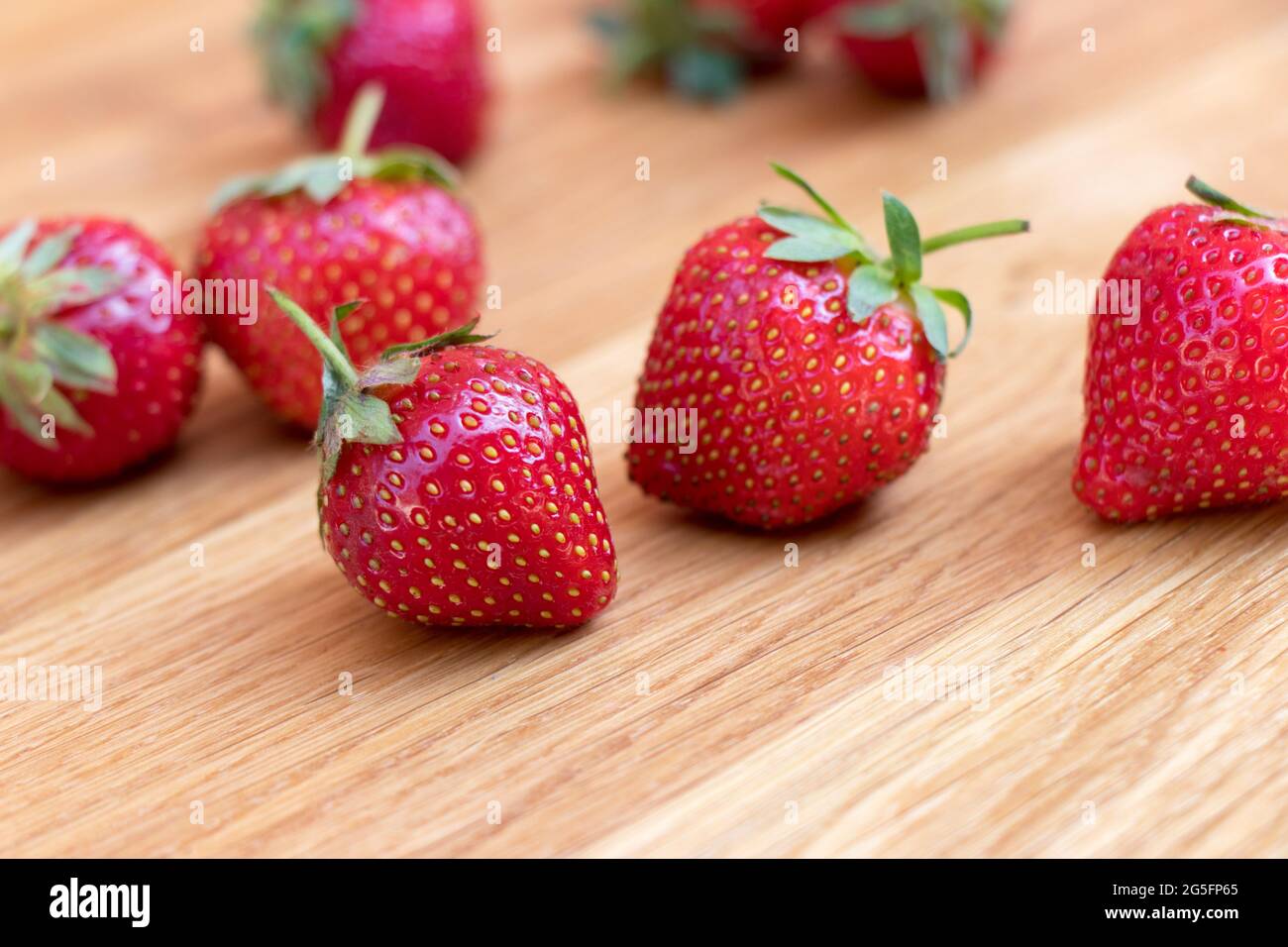 Frische Erdbeeren mit Blatt auf Holzhintergrund. Seitenansicht eingestellt. Volle Schärfentiefe. Stockfoto