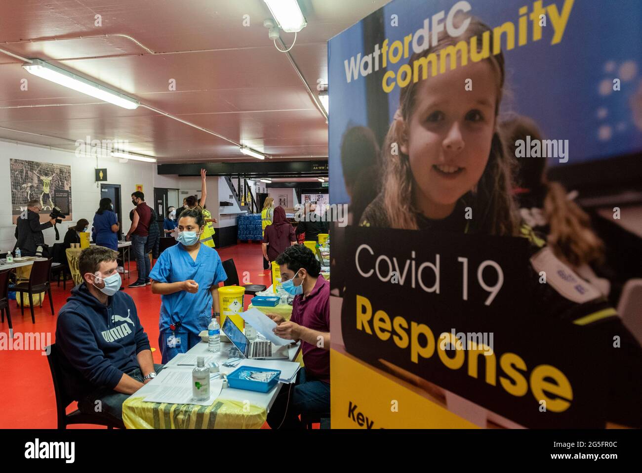 Watford, Großbritannien. 27. Juni 2021. Allgemeine Ansicht der Pop-up-Massenimpfungsklinik im Vicarage Road Stadium des Watford FC im Rahmen der Kampagne „Grab a jab“. Der NHS fördert dieses Wochenende auch eine Reihe von Walk-in-Kliniken in der Hauptstadt, um zu versuchen, die Zahl der über 18-er-Patienten, die einen Jab erhalten, zu erhöhen, da die Fälle der Delta-Variante laut Berichten auf dem Vormarsch sind. Kredit: Stephen Chung / Alamy Live Nachrichten Stockfoto