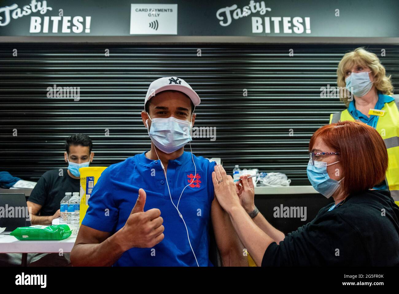 Watford, Großbritannien. 27. Juni 2021. Rafael Nunez (36) erhält im Rahmen der Kampagne „Grab a jab“ eine erste Dosis des Pfizer-Impfstoffs in einer Pop-up-Massenimpfungsklinik im Vicarage Road Stadium des FC Watford. Der NHS fördert dieses Wochenende auch eine Reihe von Walk-in-Kliniken in der Hauptstadt, um zu versuchen, die Zahl der über 18-er-Patienten, die einen Jab erhalten, zu erhöhen, da die Fälle der Delta-Variante laut Berichten auf dem Vormarsch sind. Kredit: Stephen Chung / Alamy Live Nachrichten Stockfoto