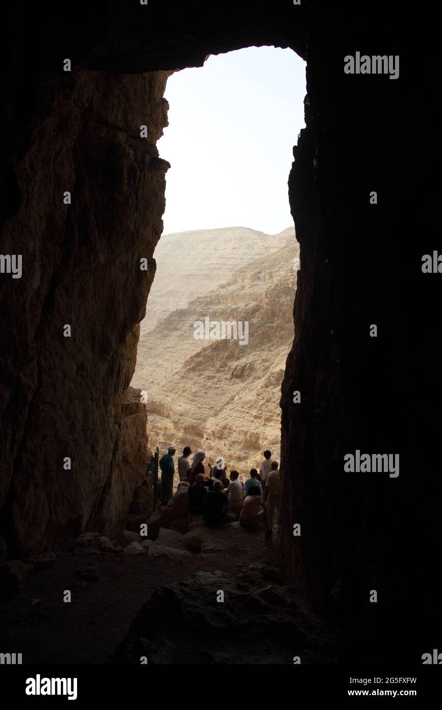 Wanderer und ihr Führer am Eingang der Murabbaat-Höhle in der Nordwand von Nachal Dragot oder Darga, wo die Bar Kochba-Briefe gefunden wurden Stockfoto