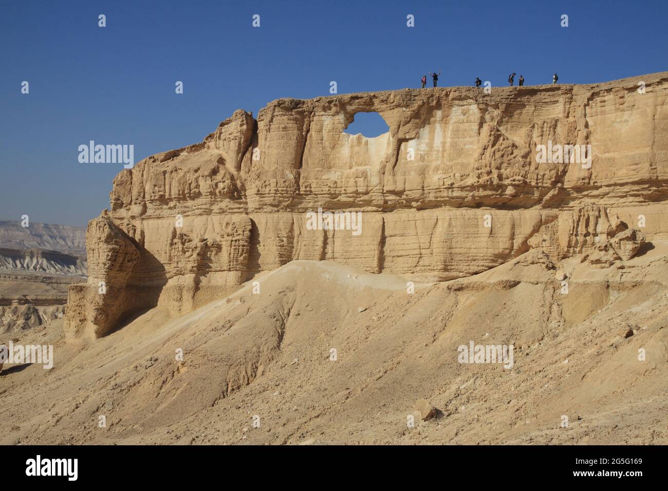 Riesiger Sandsteinfelsen in der Negev-Wüste genannt Mount Rechev mit Blick auf das trockene Flussbett von Nachal Zin, links, wird das Loch in der Mitte das Auge genannt Stockfoto