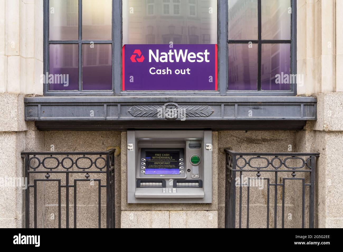 Ein NatWest-Geldautomat in einer Steinmauer einer Bank unter einem Fenster mit dem violetten Zeichen von NatWest. London - 27. Juni 2021 Stockfoto