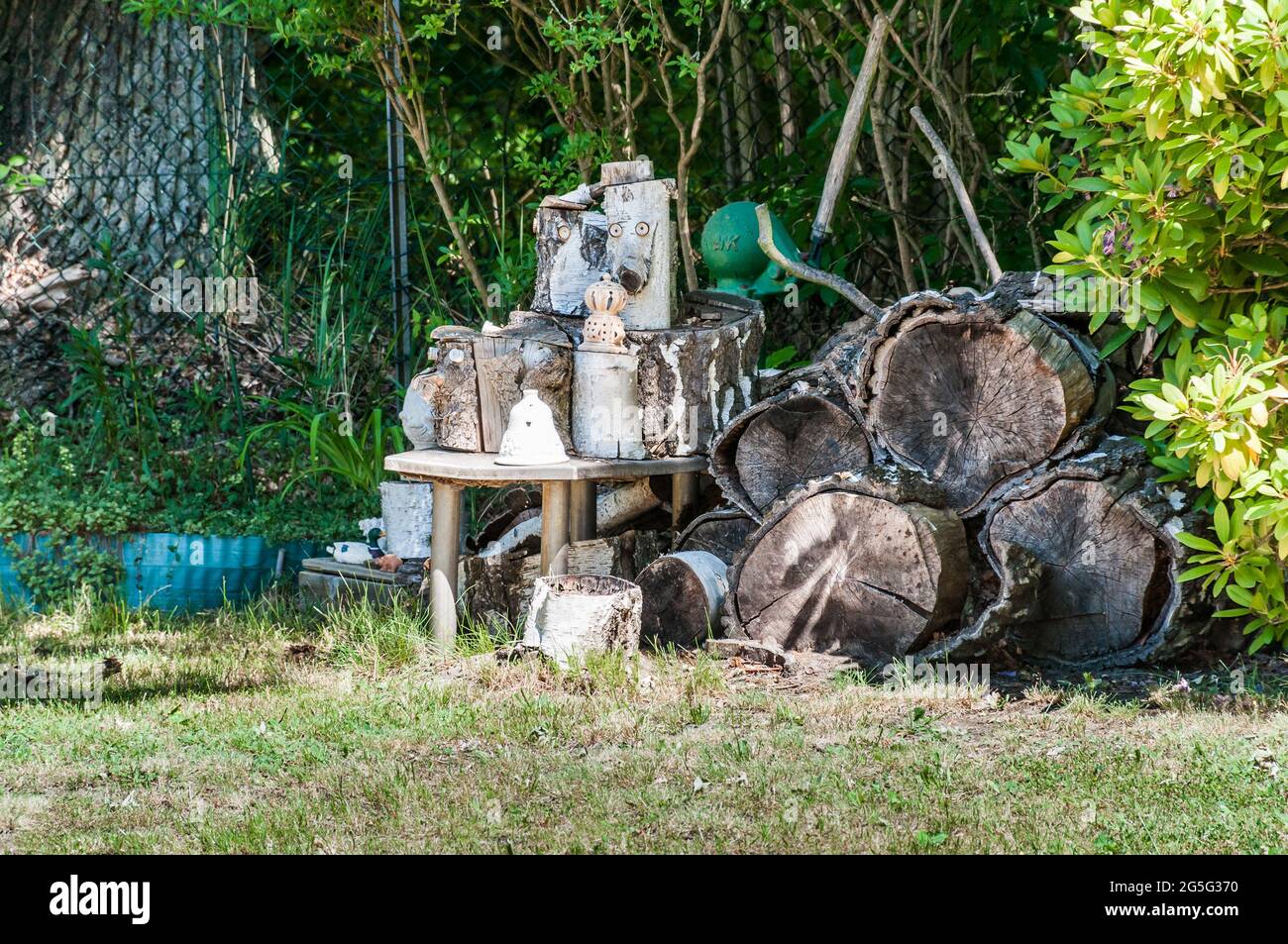 Dekoration in einem Garten. Baumscheiben wurden gestapelt und davor stand ein Tisch mit kleinen Dingen Stockfoto