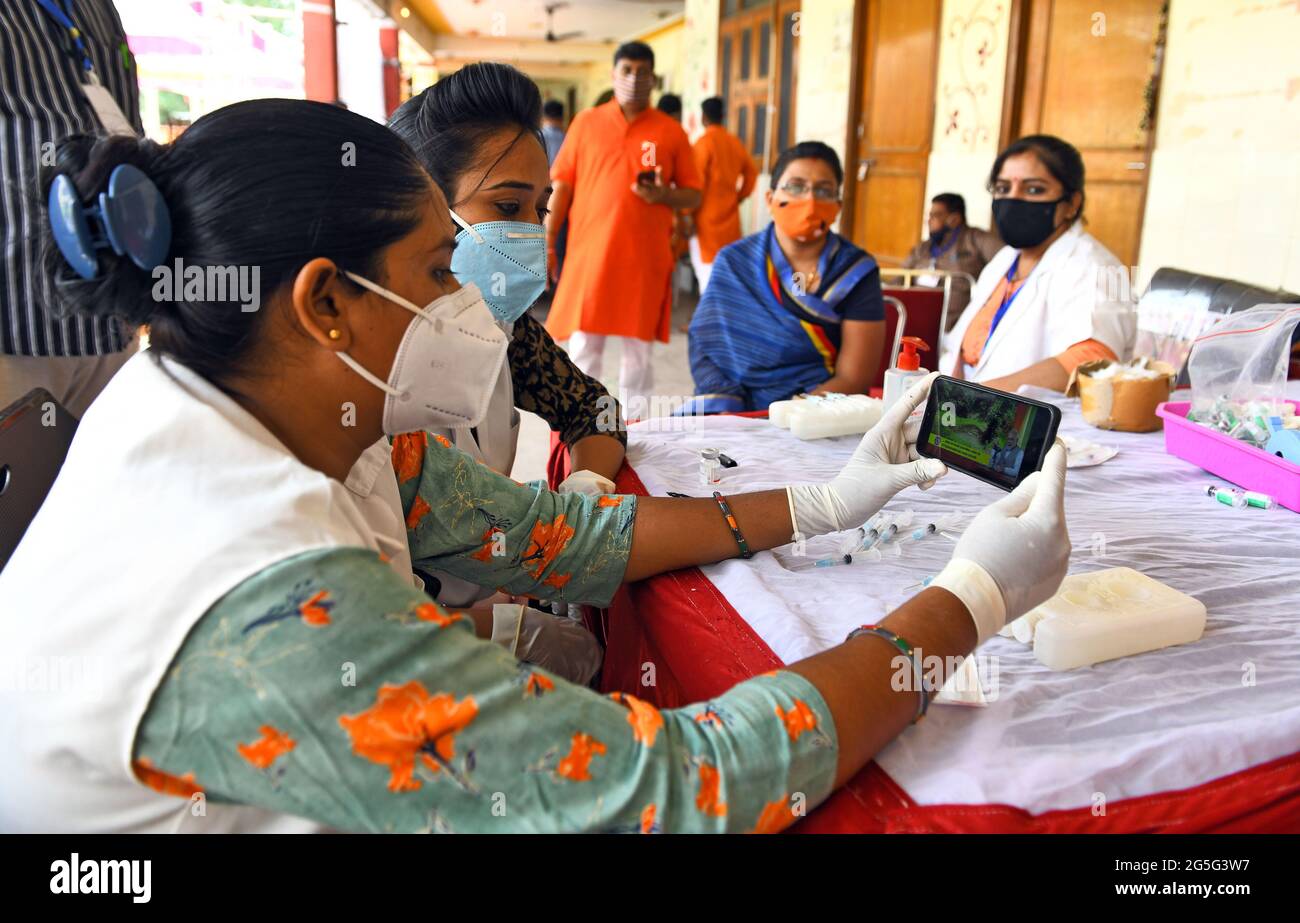 Beawar, Indien. Juni 2021. Gesundheitshelfer hören dem „Mann KI Baat“ des indischen Premierministers Narendra Modi zu, während ein Sanitäter einem Begünstigten während einer eintägigen Impfkampagne in einem Impfzentrum in Beawar eine Dosis COVID-19-Impfstoff verabreicht. PM Modi spricht über die Teilnahme Indiens an Olympischen Spielen, Impfzögerlichkeit, Regenwassernutzung und mehr. (Foto: Sumit Saleswat/Pacific Press) Quelle: Pacific Press Media Production Corp./Alamy Live News Stockfoto