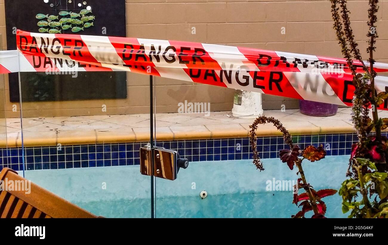 Gefahrenband am Tor des leeren Schwimmbeckens wird mit umgedrehten Konstruktionseimern auf der anderen Seite repariert Stockfoto
