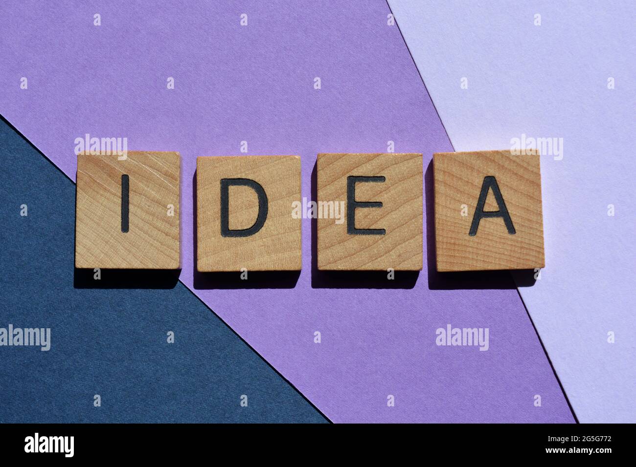 Idee, Wort in Holzalphabetbuchstaben isoliert auf violettem und blauem Hintergrund als Banner-Überschrift Stockfoto