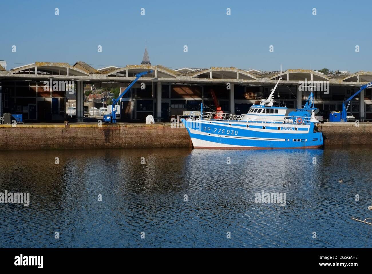 Smart aussehendes blaues Boot, das sich im Wasser des Hafens von Dieppe France widerspiegelt Stockfoto