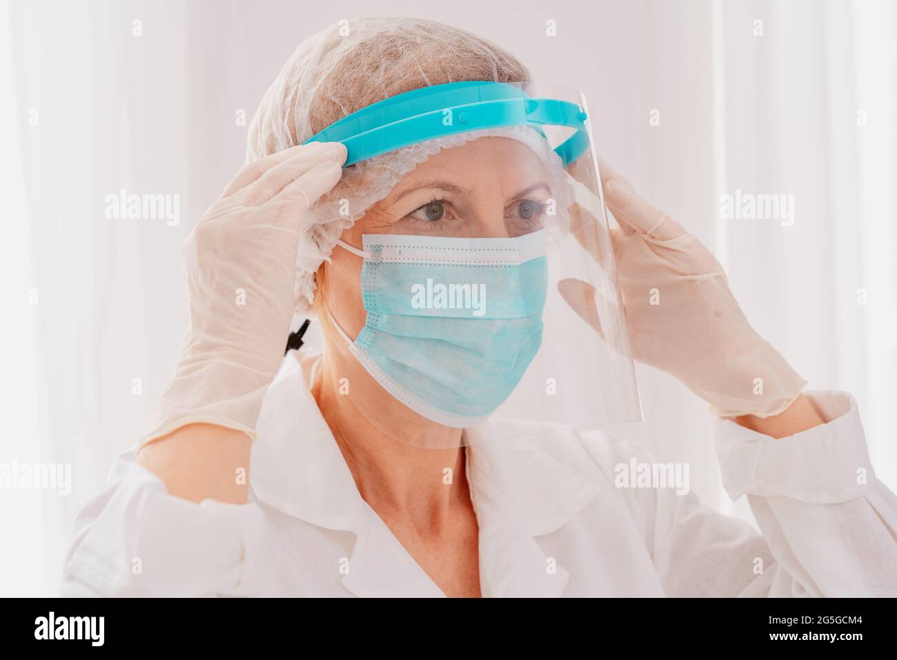 Der Arzt stellt den Gesichtsschutz gegen das Covid-19-Virus ein Stockfoto