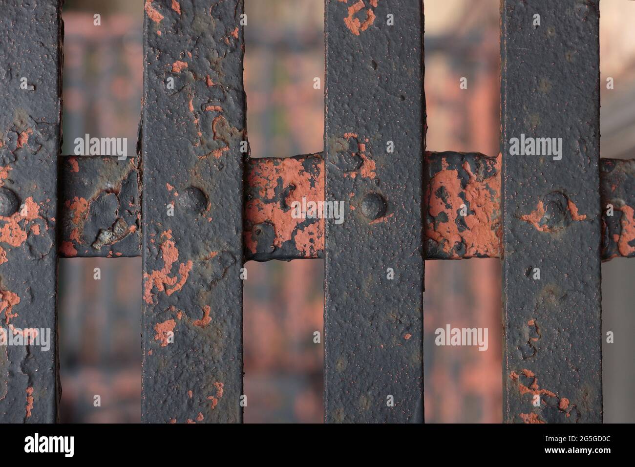 Verrostete, abblätternde Farbe auf überkreuzenden Metallstangen mit Schrauben bilden einen düsteren, urbanen Hintergrund in tiefbrauner, oranger, verbrannter Umbra, Terrakotta-Erde Stockfoto