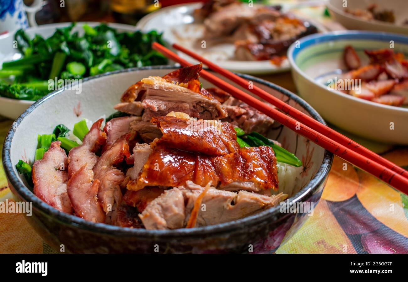 Eine herzhafte Mahlzeit mit kantonesischer gebratener Ente, gebratenem Schweinefleisch, grünem Gemüse und Reis. Stockfoto