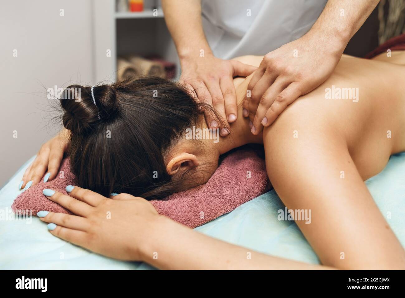 Ein Mann ist ein Chiropraktiker, der eine Massage für eine Frau im Nacken und Trapezmuskeln in seinem Büro macht. Stockfoto