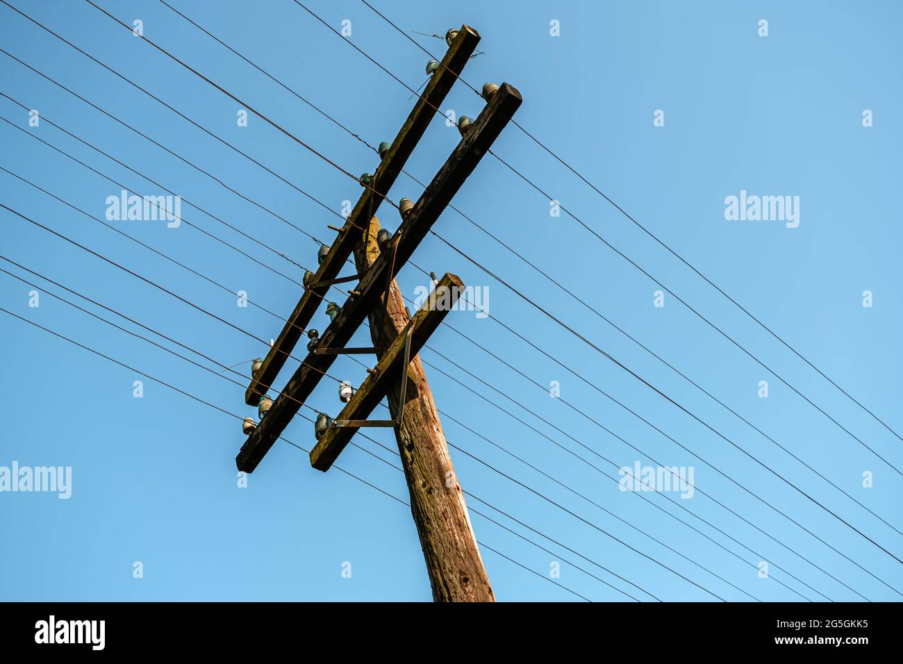 Ein hölzerner, elektrischer Mast an den Bahngleisen Stockfoto