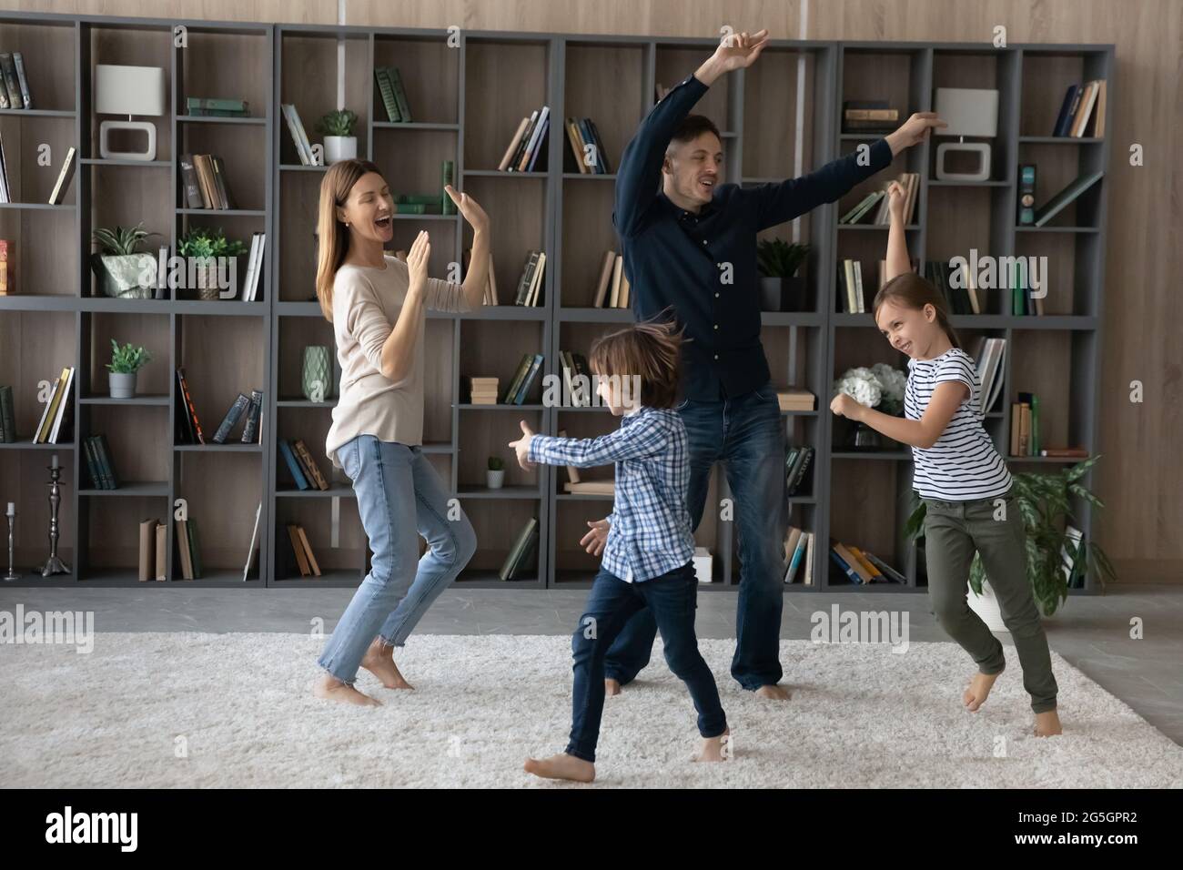 Glückliche Eltern mit Kindern tanzen zu Hause zusammen Stockfoto