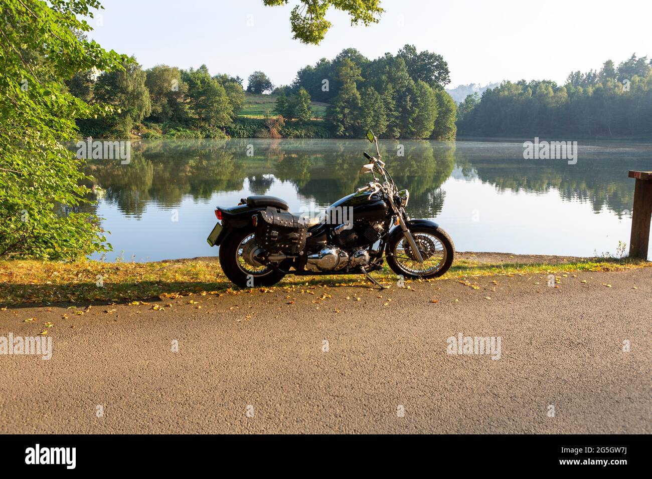 Schwarzes Custom klassisches Motorrad, das im Herbst am See geparkt wurde Stockfoto