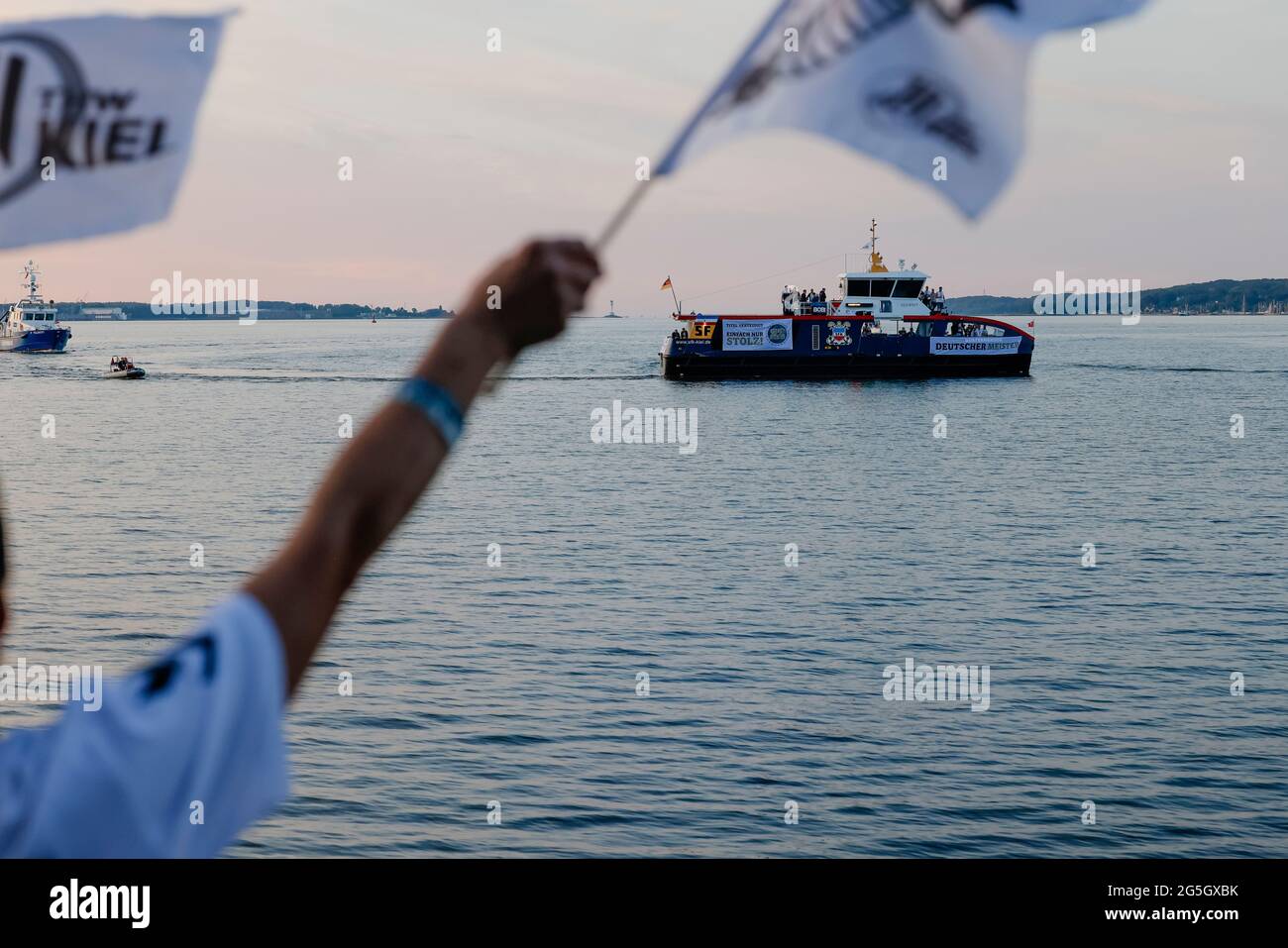 Kiel, Deutschland. Juni 2021. Fans des deutschen Handballmeisters THW Kiel jubeln dem Team zu. Mit der Elektrofähre 'MS Düsternbrook' waren die Kieler Handballer entlang der Wasserstraße in die Kiellinie gefahren, um sich und den WM-Pokal den wartenden Anhängern zu präsentieren. Die Kielers hatten am 27.06.2021 ihren 22. DM-Titel gewonnen. Quelle: Frank Molter/dpa/Alamy Live News Stockfoto