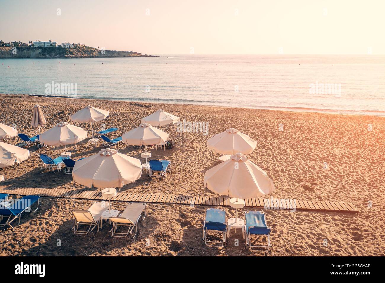 Leere Liegen mit Sonnenschirmen, sandige Strandküste ohne Menschen am Sommertag. Stockfoto