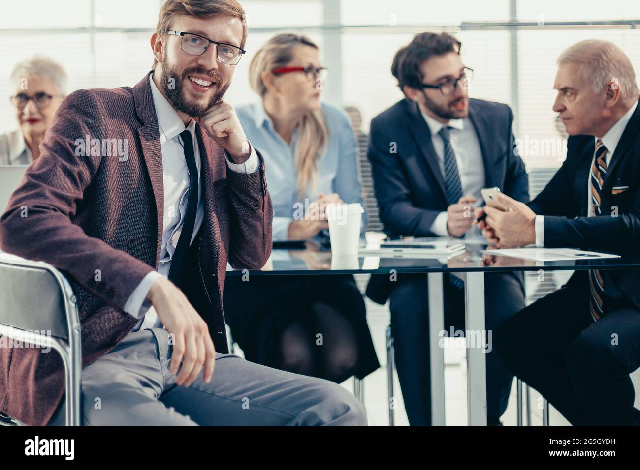 Lächelnder Geschäftsmann sitzt an einem Büroschalter. Stockfoto