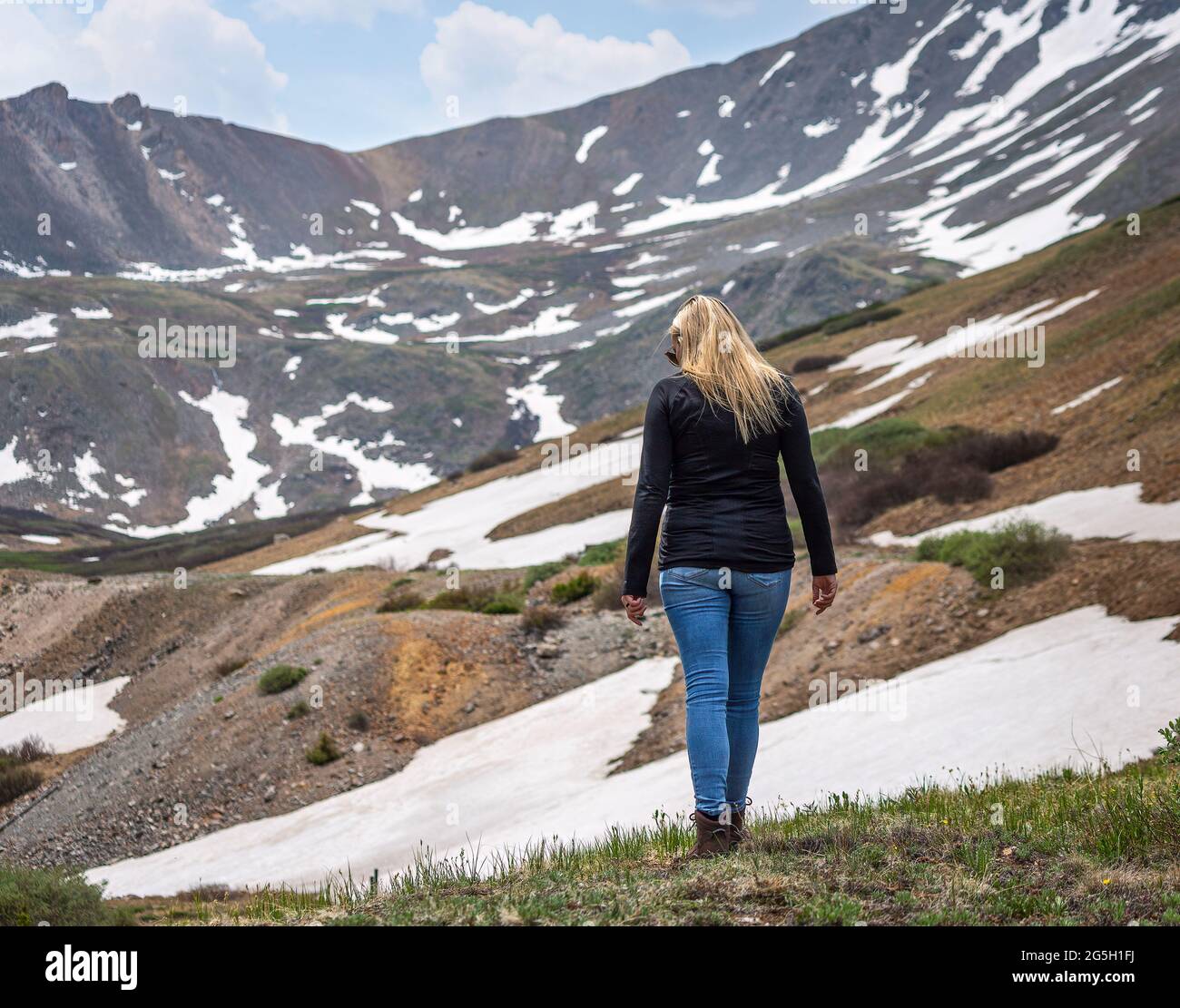 Schöne Frau, die auf dem hohen Berggipfel entlang geht Stockfoto