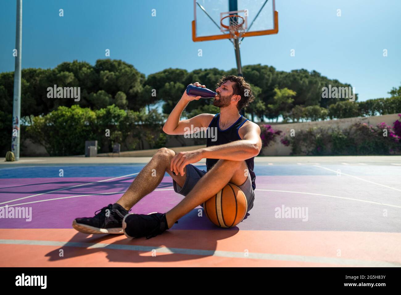 Müde Handsome man Basketballspieler trinkt Wasser nach dem Training. Auffüllung des Wasserhaushalten Stockfoto