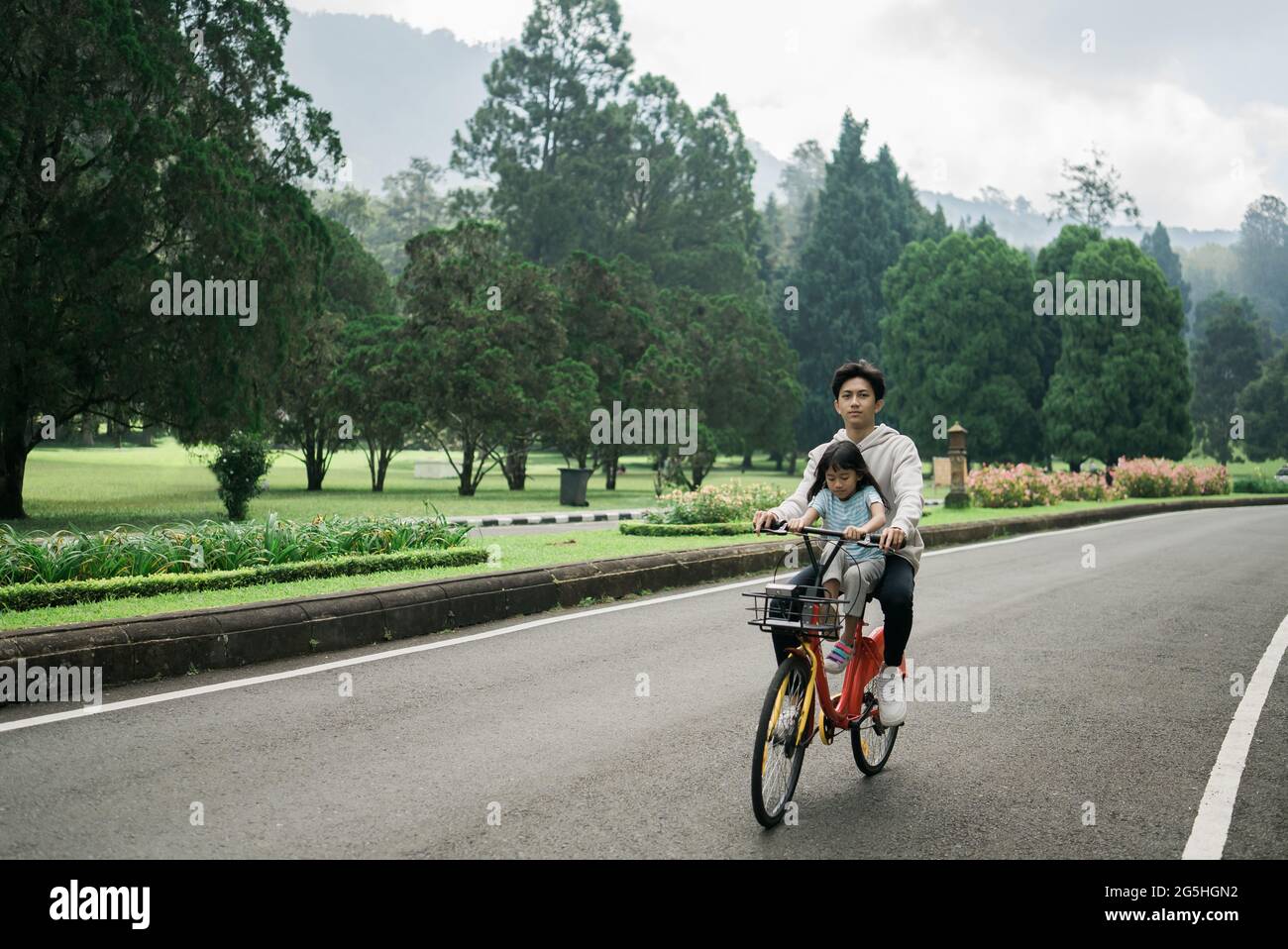 Bruder nimmt seine Schwester mit auf lustige Fahrradtour im Park Stockfoto
