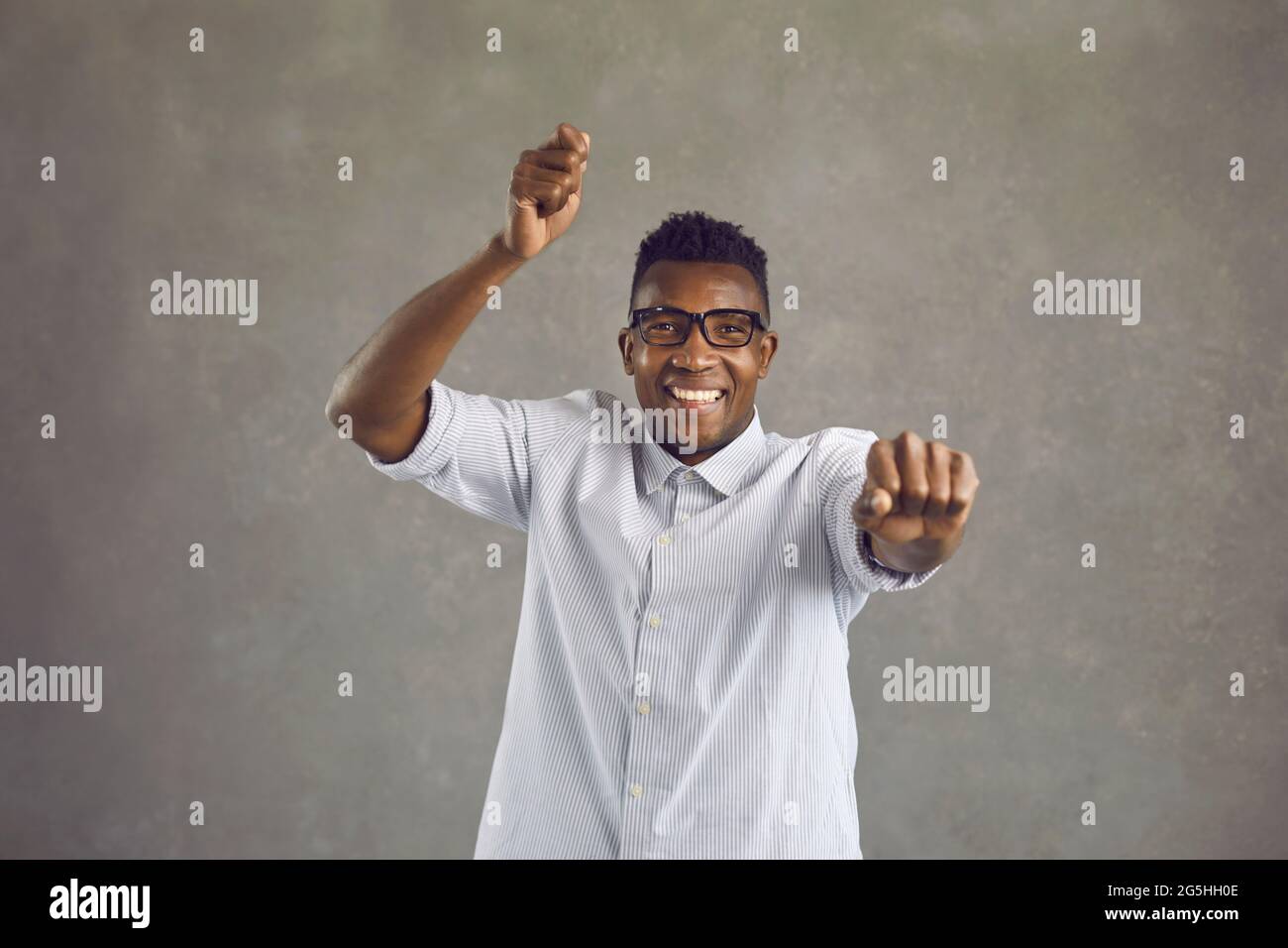 Studioaufnahme eines glücklichen jungen Afro-Amerikaners, der im gangnam-Stil tanzt und lächelt Stockfoto