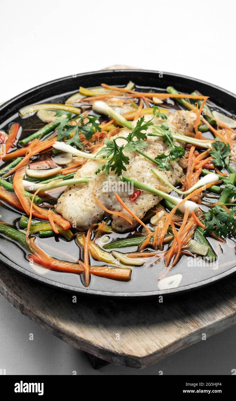 chinesisches, kantonesisches Fischfilet im gedämpften, würzigen Stil mit Gemüse Heizplatte Stockfoto