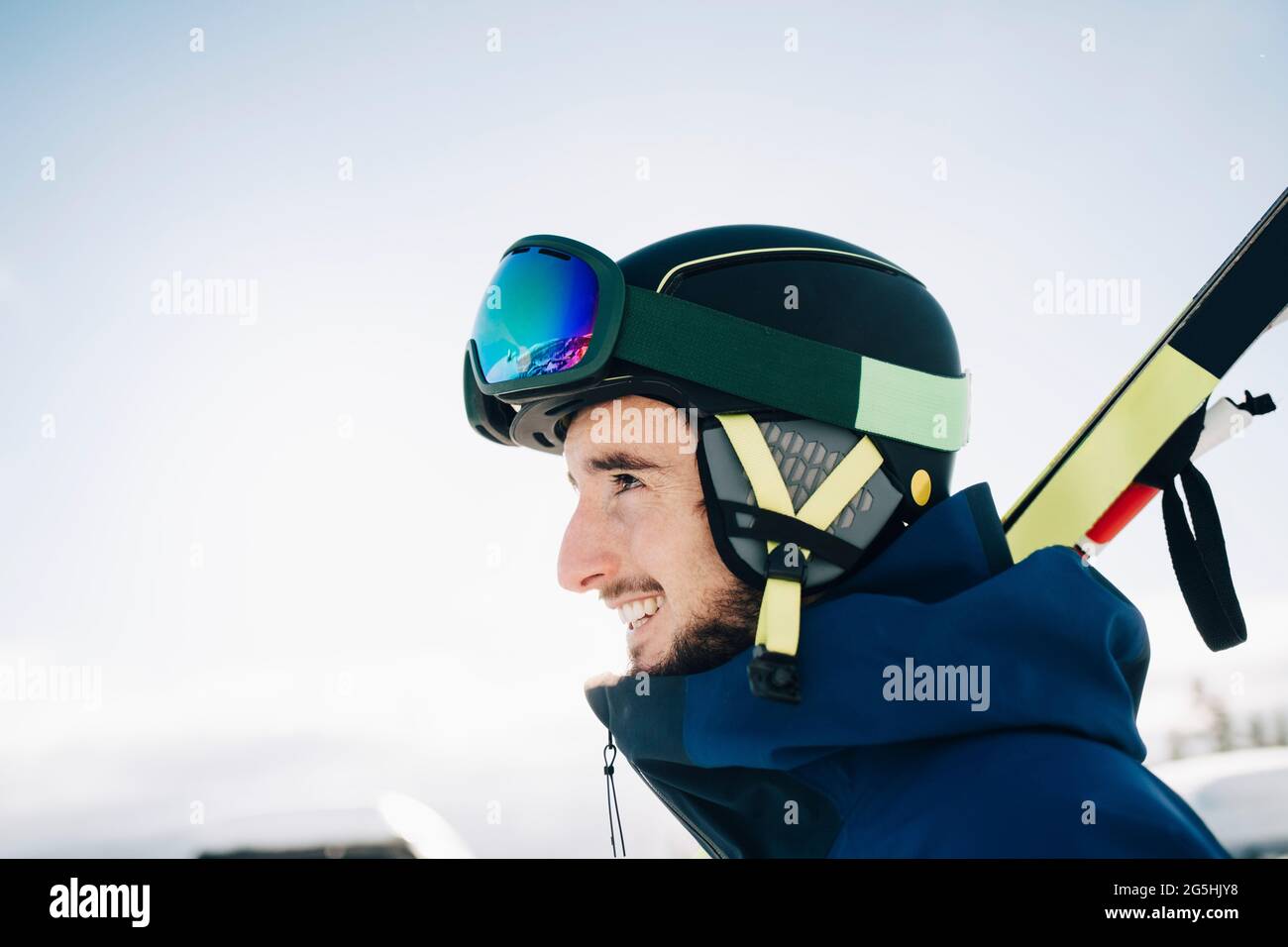 Glücklicher Mann mit Skibrille und Helm, während er zum Himmel blickt Stockfoto