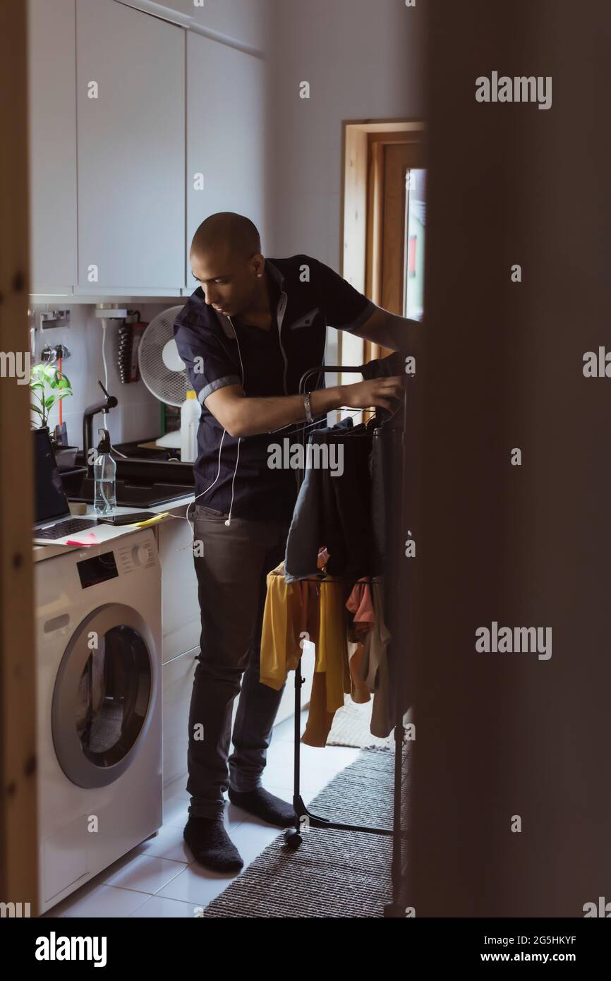 Mann, der die Waschmaschine ansieht, während er im Hauswirtschaftsraum seine Wäsche wäscht Stockfoto