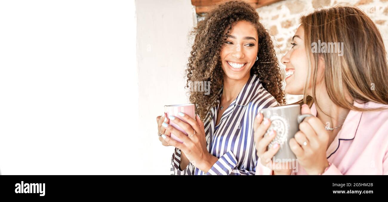 Multirassische Frauen, die lächeln und sich gegenseitig mit einer Teetake in einem Pyjama betrachten, sind gerade aufgeweckt. Neue normale homosexuelle Familien Beziehung und Gewohnheiten täglich li Stockfoto