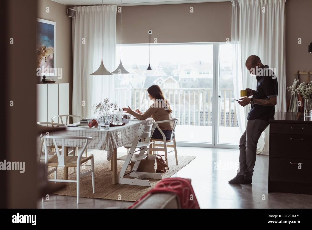 Weibliche Unternehmerin, die arbeitet, während ein männlicher Kollege zu Hause hinter sich steht Stockfoto
