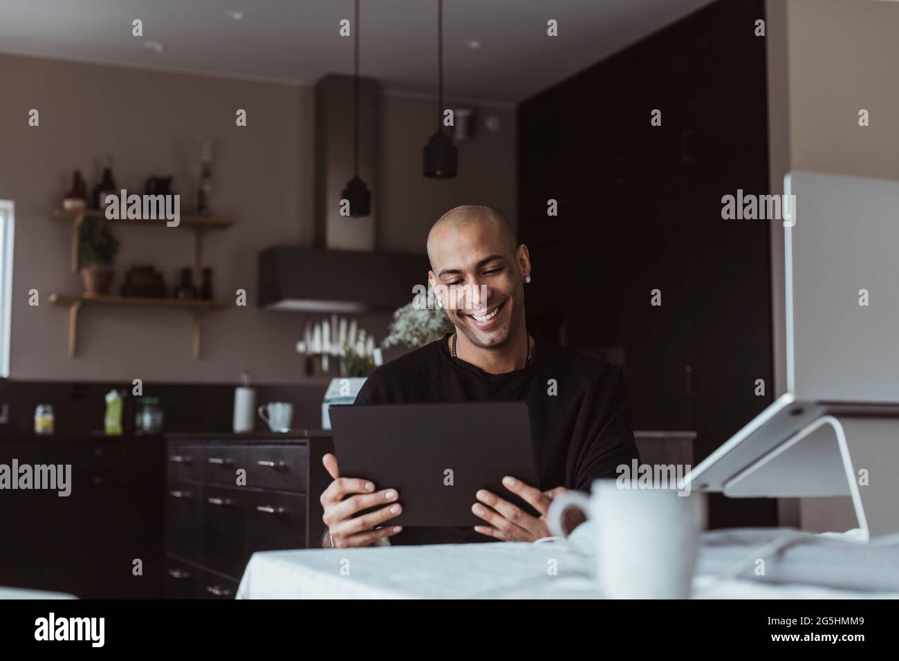 Lächelnder Geschäftsmann, der zu Hause mit einem digitalen Tablet arbeitet Stockfoto