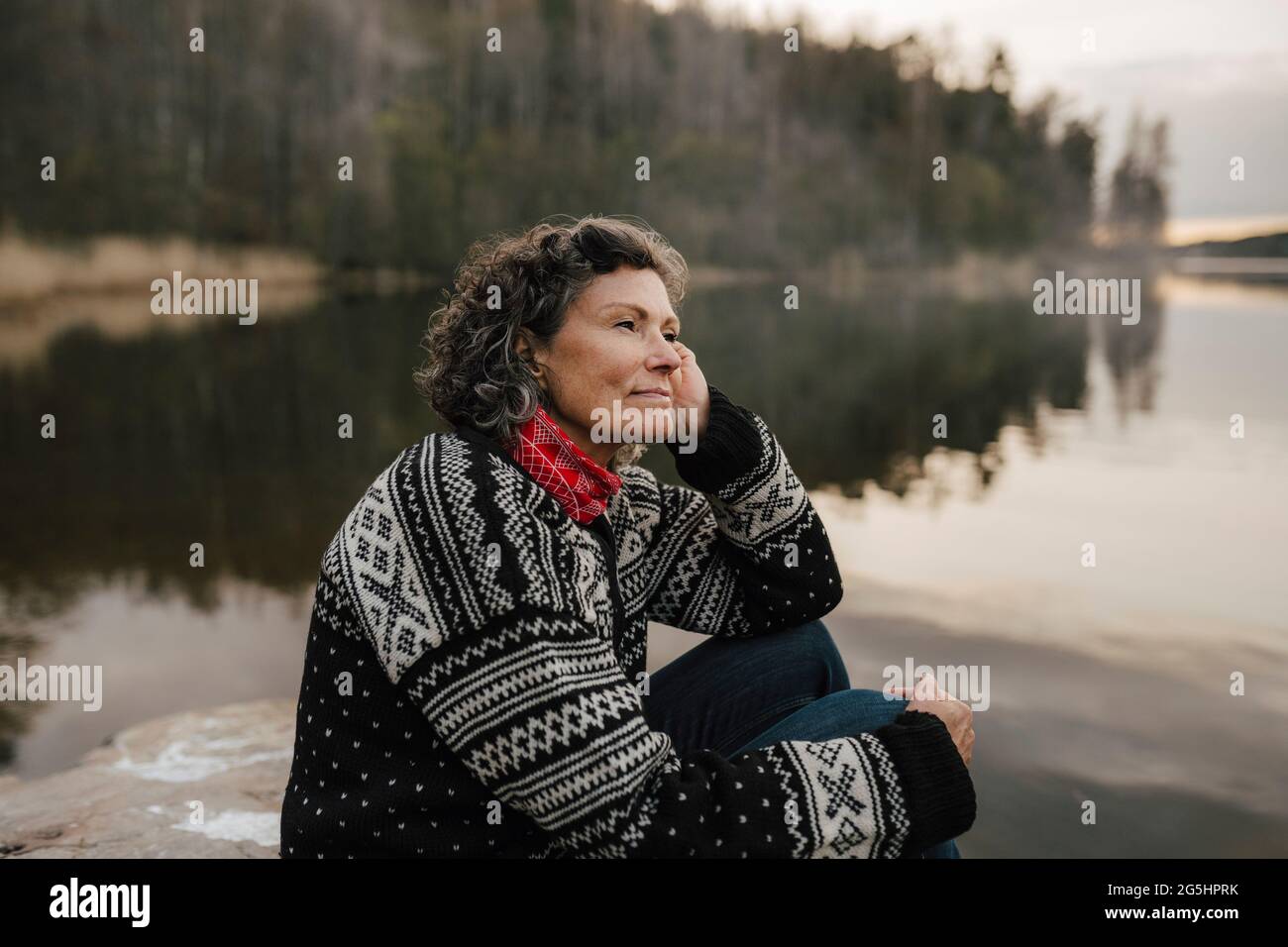 Kaukasische Wandererin, die beim Sitzen am See nachdenkt Stockfoto