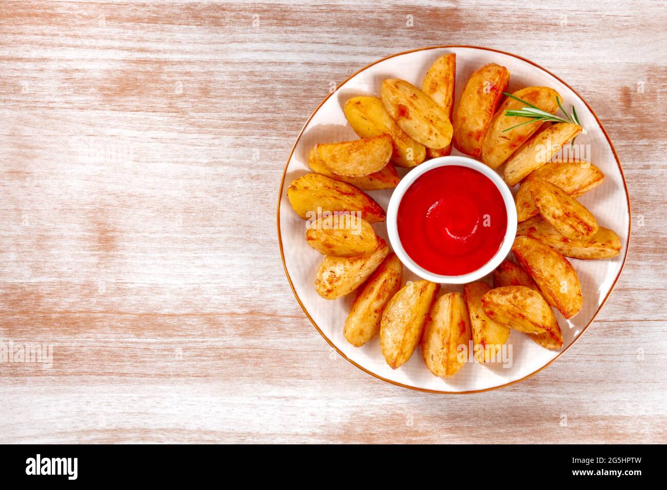 Gebackene Kartoffelkeile mit Kopierfläche, aufgenommen von oben auf einem rustikalen Hintergrund Stockfoto