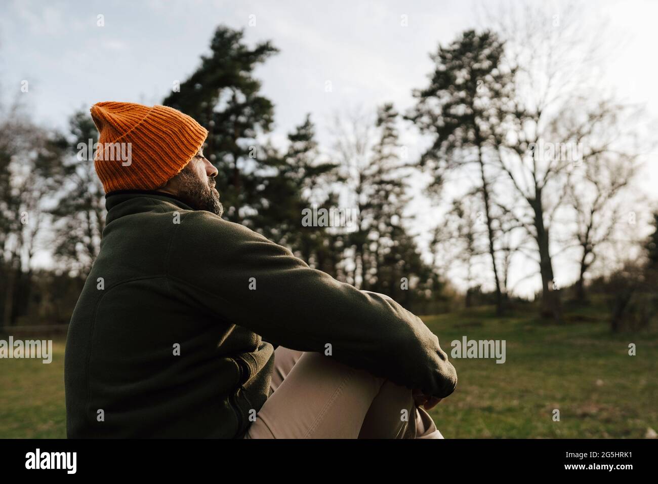 Reifer männlicher Wanderer, der im Wald sitzt Stockfoto